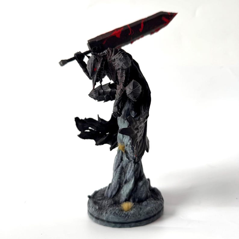 Puede incluir: Una figura detallada de un guerrero con armadura oscura en posici&oacute;n agachada, equilibr&aacute;ndose sobre una base rocosa. El personaje viste una armadura negra texturizada con detalles rojos y lleva una espada masiva sobre los hombros con marcas rojas.