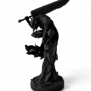 Puede incluir: Una figura negra mate de un guerrero con armadura completa de placas sobre una base texturizada. La figura est&aacute; inclinada hacia adelante, sosteniendo una espada grande y pesada sobre los hombros con ambas manos. Una capa fluida se extiende desde la espalda.