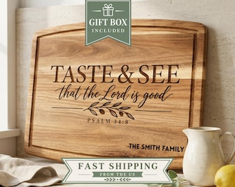 May include: A rectangular wooden cutting board with a juice groove, engraved with the text TASTE & SEE that the Lord is good, PSALM 34:8, and THE SMITH FAMILY, featuring a decorative olive branch illustration centered below the main text.