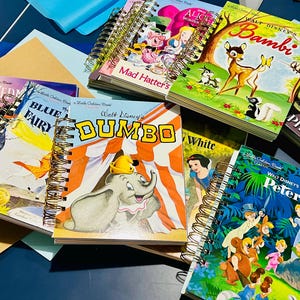 May include: A collection of spiral-bound Little Golden Books featuring classic Disney characters including Dumbo, Bambi, Peter Pan, and Alice in Wonderland. Each book has a colorful illustrated cover with iconic scenes and bold titles printed on the front.