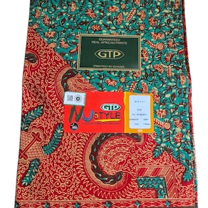 Puede incluir: Tela doblada con un patrón vibrante. La parte superior presenta un fondo turquesa con un diseño floral rojo y amarillo. La sección inferior es predominantemente roja con patrones intrincados y detalles turquesa. La tela incluye el texto "GARANTIZADO IMPRESIONES AFRICANAS REALES".