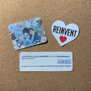 May include: A collection of stickers on a corkboard. One sticker features a photo of two people, surrounded by decorative elements. Another is heart-shaped with "REINVENT" and a red heart. A third sticker has text.