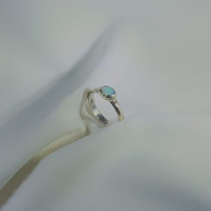 May include: A silver ring with a light blue oval opal gemstone.