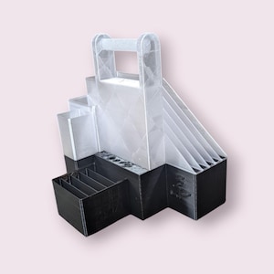 May include: A clear and black organizer with a handle. The organizer has multiple compartments, including a tiered section, a small drawer, and a section with holes. The design is geometric and modern, suitable for various organizational needs.