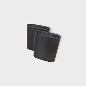 May include: Two black, cylindrical objects with a slightly curved shape. Each has a rectangular opening at the top with two oval holes. The objects are positioned at a slight angle against a white background.