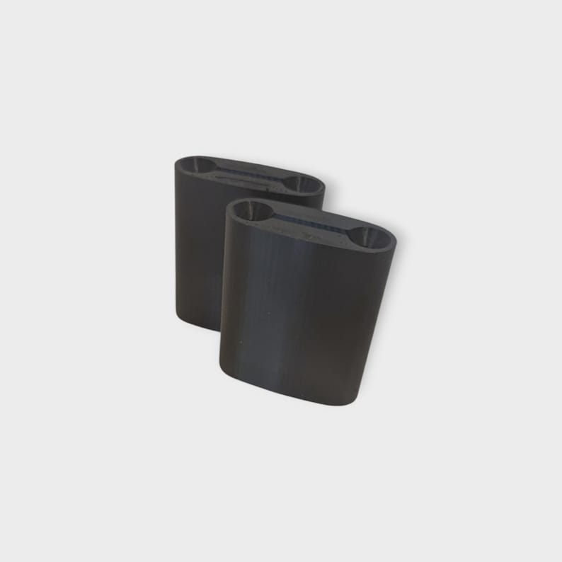 May include: Two black, cylindrical objects with a slightly curved shape. Each has a rectangular opening at the top with two oval holes. The objects are positioned at a slight angle against a white background.