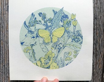 May include: A print featuring a deer, butterfly, and floral design in a circular composition. The artwork uses shades of blue and yellow on a cream background. The deer is on the left, and the butterfly is in the center.