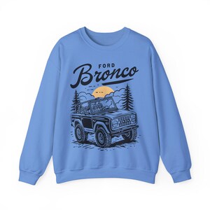 The Ford Bronco Adventure Sweatshirt exudes a sense of adventure and ruggedness, perfect for outdoor enthusiasts and fans of the iconic vehicle. This cozy sweatshirt is made with a medium-heavy fabric blend of 50% cotton and 50% polyester, providing