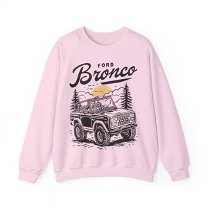 The Ford Bronco Adventure Sweatshirt exudes a sense of adventure and ruggedness, perfect for outdoor enthusiasts and fans of the iconic vehicle. This cozy sweatshirt is made with a medium-heavy fabric blend of 50% cotton and 50% polyester, providing