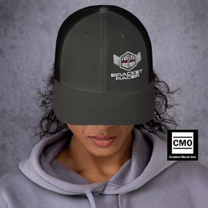 Puede incluir: Gorra de camionero gris y negra con el texto "Fueled by Horsepower Bracket Racer" en blanco. La gorra tiene una parte trasera de malla y una visera curva. La gorra la lleva una persona.