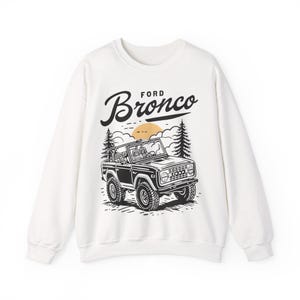 The Ford Bronco Adventure Sweatshirt exudes a sense of adventure and ruggedness, perfect for outdoor enthusiasts and fans of the iconic vehicle. This cozy sweatshirt is made with a medium-heavy fabric blend of 50% cotton and 50% polyester, providing