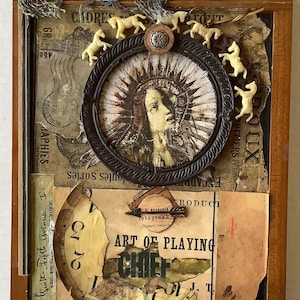 May include: A rectangular wooden box lid featuring a collage of vintage paper ephemera, a circular frame containing a portrait of a person, four small cream-colored horse figurines, a metal arrow, and text including ART OF PLAYING and CHIEF.