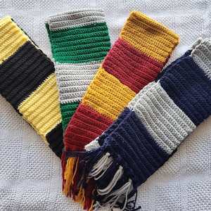 May include: Five crocheted scarves in different color combinations. The scarves are striped with yellow, black, green, white, red, and blue.