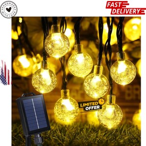May include: String of solar-powered, round, warm white LED lights. The lights are in a cluster, with a solar panel and the text "LIMITED OFFER". The lights are on a black wire and are set against a background of green grass.