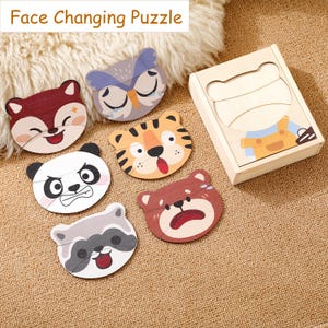 K&ouml;nnte beinhalten: Holz-Gesichtswechsel-Puzzle mit sechs Tiergesichtern: Fuchs, Eule, Tiger, Panda, B&auml;r und Waschb&auml;r. Jedes Tiergesicht hat zwei Ausdr&uuml;cke. Das Set enth&auml;lt eine Holzkiste mit einem B&auml;ren-Design. Der Text "Face Changing Puzzle" steht oben.