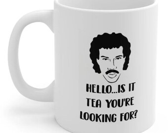 Taza blanca de Lionel Richie con la frase "Hola..." y un estampado humorístico.
