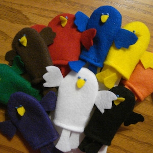 May include: A set of ten felt finger puppets in various colors, including green, blue, white, brown, orange, yellow, and purple. Each puppet has a simple bird design with a beak and eyes.