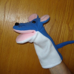May include: Blue and white hand puppet shaped like a mouse with pink ears and a pink mouth.