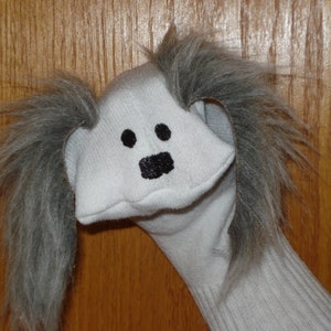 Hunddocka med grå pälsiga öron, rörlig mun, berättande