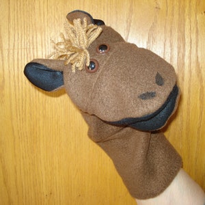 May include: Brown felt hand puppet with black felt ears and mouth. The puppet has large brown plastic eyes and a brown felt mane.