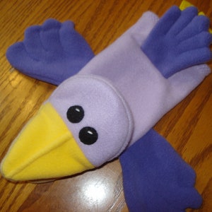 May include: Purple and yellow felt hand puppet shaped like a bird with large eyes.