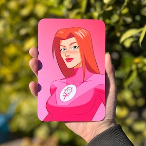 May include: A pink and white illustration of a woman with red hair wearing a pink suit with a symbol of a circle with a female symbol inside. The background is pink.