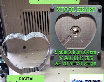 Könnte beinhalten: Ein metallischer herzförmiger Ausstecher neben einer grauen rechteckigen Platte mit herzförmigem Ausschnitt. Die Platte zeigt grünen Text: XTOOL HEART, 9.5cm X 8cm X 4cm, VALUE 35, X=70 Y=70 Z=40 und STL,XS,SVG file only.