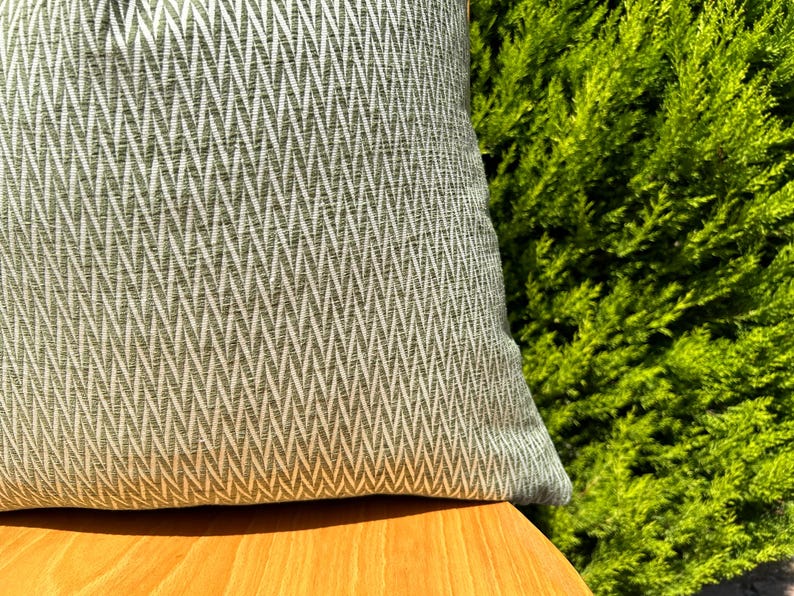 May include: A green and white chevron patterned throw pillow on a wooden surface.
