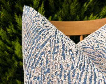 May include: Two blue and white patterned throw pillows with a wavy design. The pillows are on a wooden chair.
