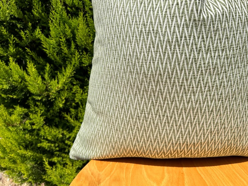 May include: A green and white chevron patterned throw pillow on a wooden surface.
