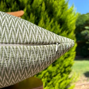 May include: A green and white pillow with a chevron pattern and a zipper closure.