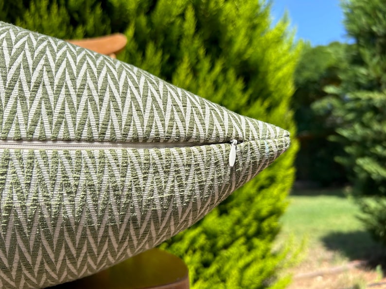 May include: A green and white pillow with a chevron pattern and a zipper closure.