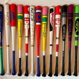 May include: A collection of twelve baseball bats with various color schemes and designs. The bats feature colors like blue, red, pink, green, and yellow, with some having text and graphics. The bats are arranged vertically, showcasing their unique patterns and branding.