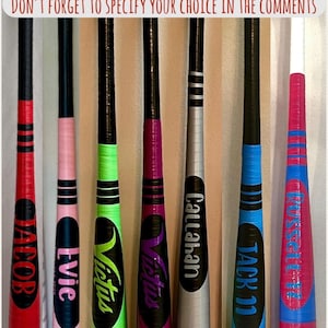 May include: A collection of personalized baseball bats in various colors, including red, pink, green, purple, silver, blue, and pink. Each bat features a name or team logo, with the text "MORE COLORS AVAILABLE!" and "DON'T FORGET TO SPECIFY YOUR CHOICE IN THE COMMENTS".