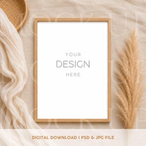 Könnte beinhalten: Ein Holzbilderrahmen mit dem Text "YOUR DESIGN HERE" auf weißem Hintergrund. Der Rahmen ist von beigem Stoff, einem geflochtenen Korb und getrocknetem Ziergras umgeben. Die Worte "DIGITAL DOWNLOAD I PSD & JPG FILE" stehen unten.