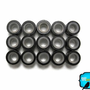May include: A set of 16 black hair beads with a silver interior. The beads are arranged in a grid pattern.
