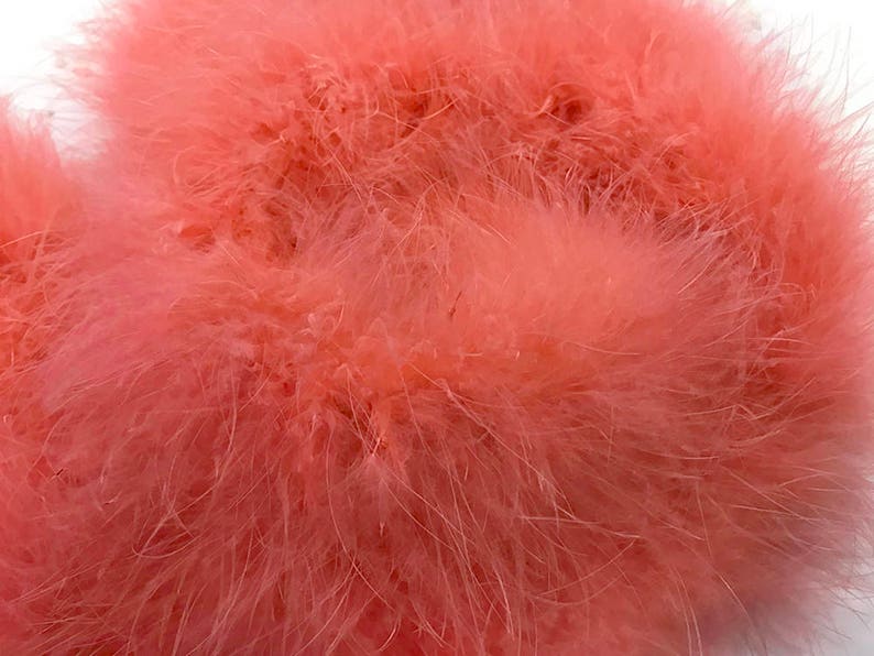 May include: A close-up of a bunch of soft, pink feathers. The feathers are fluffy and delicate, and they are perfect for crafting or decorating.