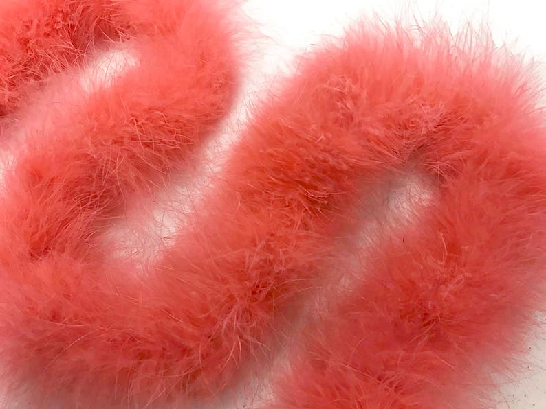May include: A close-up of a bundle of pink feather boas. The boas are soft and fluffy, and they are perfect for adding a touch of glamour to any outfit.