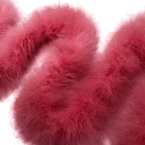 Puede incluir: Primer plano de tres hebras de boa de plumas rosa. La boa es suave y esponjosa, y es perfecta para a&ntilde;adir un toque de glamour a cualquier atuendo.
