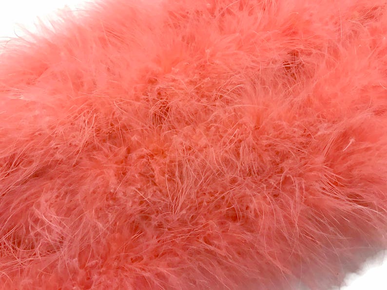 May include: A close-up of a soft, peach-colored feather boa. The boa is made of fluffy feathers and is perfect for adding a touch of glamour to any outfit.