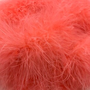 May include: A close-up of a bunch of soft, pink feathers. The feathers are fluffy and have a delicate texture.