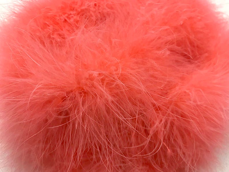 May include: A close-up of a bunch of soft, pink feathers. The feathers are fluffy and have a delicate texture.