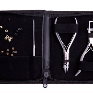 Puede incluir: Una funda negra con cremallera que contiene herramientas y cuentas para extensiones de cabello de micro-enlace. La funda tiene dos compartimentos, uno con una herramienta y el otro con dos herramientas y cuentas. Las herramientas son alicates de metal plateado y una pequeña herramienta de metal plateado. Las cuentas son pequeñas y vienen en varios tonos de marrón.