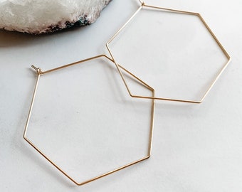 May include: A pair of gold hexagonal hoop earrings. The earrings are simple and elegant, and would make a great addition to any jewelry collection.