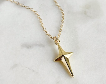 May include: A gold chain necklace with a star-shaped pendant. The star is a geometric design with sharp points.
