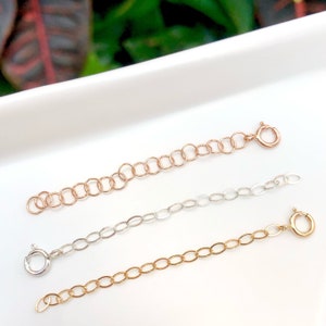 May include: Three gold chain extenders, one in rose gold, one in silver, and one in yellow gold. Each extender has a lobster clasp.