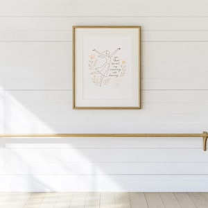 May include: A framed print featuring a line drawing of a dancer and the text "You have turned my morning into dancing." Below, a wooden rod with decorative ends is mounted on a white wall.