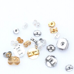 May include: Assortment of earring backs in gold, silver, and nickel finishes. The backs are made of metal and have a variety of shapes and sizes.