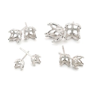 May include: Four pairs of silver stud earring settings. Each setting has a floral design with prongs for gemstones. The earrings are shown against a white backdrop.