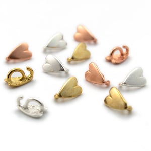 Puede incluir: Surtido de cierres de metal en forma de corazón en acabados dorado, plateado y oro rosa. Estos cierres son perfectos para agregar un toque de elegancia a los proyectos de joyería.